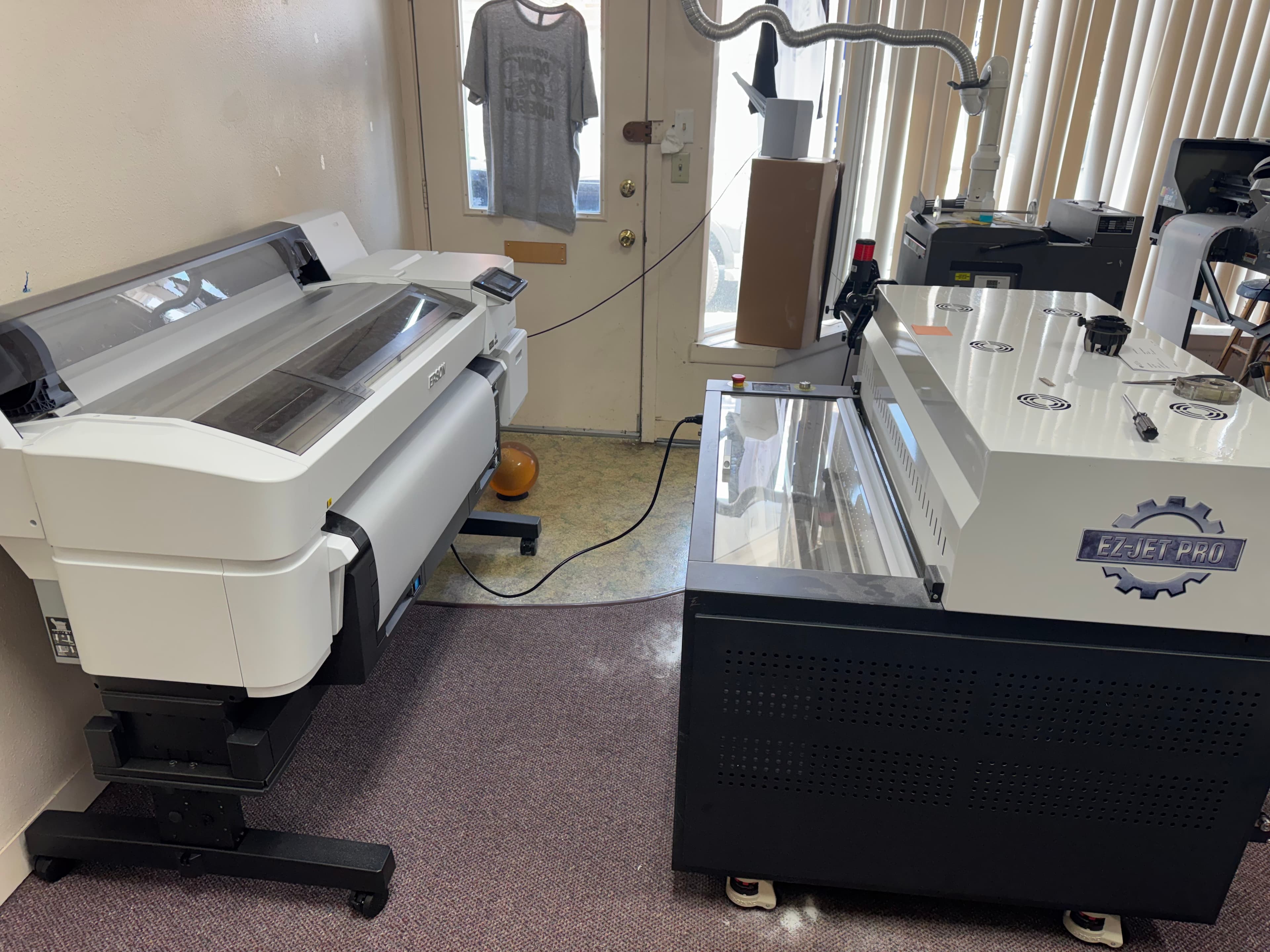 Large white Epson printer and EZ-JET PRO industrial machine in a professional printing workshop.