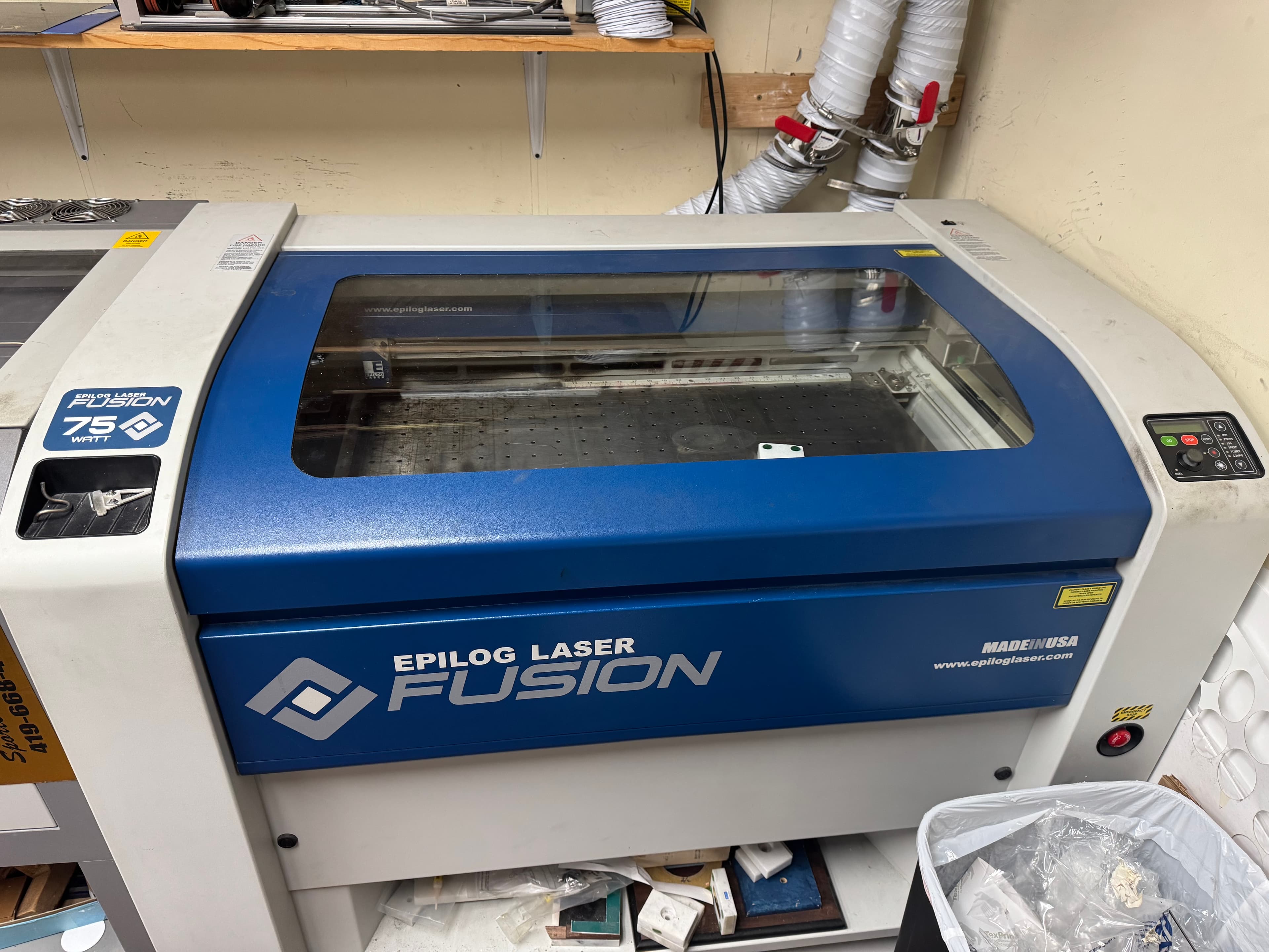 Industrial Epilog Laser Fusion 75 Watt cutter with a blue front and clear glass lid.